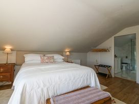A bedroom with a bed lamps nightstands open clothes rack and an ensuite bathroom at Holly Cottage in Llechwedd near Conwy