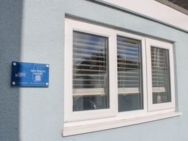 A window and sign on the exterior of Old Police House in Salcombe