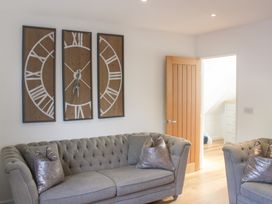 A living room with a clock and two grey sofas at Old Police House in Salcombe