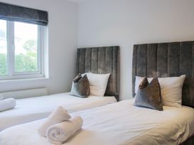 A bedroom with two beds and a window at Old Police House Salcombe