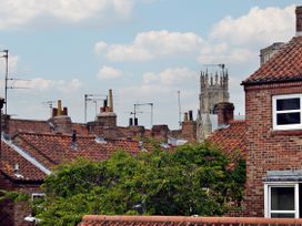 View of brick houses with tiled roofs and chimney stacks with a church tower in the background in York