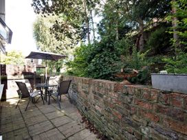 An outdoor patio area with a table four chairs and an umbrella next to a brick wall with plants at New Tower House 10 Pear Tree Court York