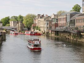 A river with boats and buildings along the riverside at New Tower House- 10 Pear Tree Court in York