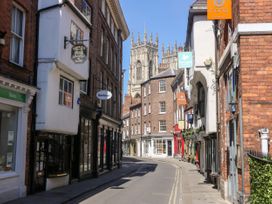 A narrow street with shops and signs and a cathedral in the background at New Tower House- 10 Pear Tree Court in York