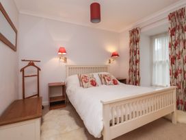 A bedroom with a white bed with floral pillows two red wall lamps wooden furniture and floral curtains at New Tower House- 10 Pear Tree Court in York