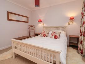 A bedroom with a white wooden bed with floral pillows bedside tables wall lamps a mirror and floral curtains at New Tower House 10 Pear Tree Court in York