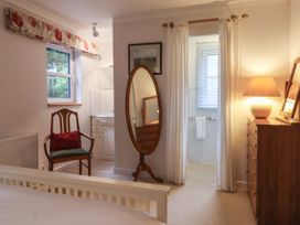 A bedroom with a wooden chair and red cushion near a window a standing oval mirror and a dresser with a lamp at New Tower House- 10 Pear Tree Court in York