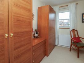 A room with wooden wardrobes drawers a chair with a red cushion and a window with white curtains at New Tower House 10 Pear Tree Court York
