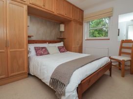 A bedroom with a double bed framed by built-in wooden wardrobes a wooden chair near a window and neutral bedding at New Tower House- 10 Pear Tree Court in York