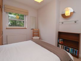 A bedroom with a bed a wooden chair a bookshelf with books a wall mirror and a window at New Tower House- 10 Pear Tree Court in York