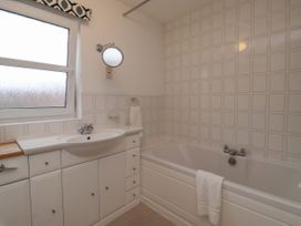 A bathroom with a bathtub a sink with cabinets and a window at New Tower House- 10 Pear Tree Court York