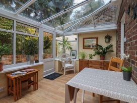 A conservatory with plants a wicker chair a wooden sideboard and a table at New Tower House- 10 Pear Tree Court in York