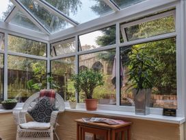 A conservatory with a wicker chair a small table magazines and several potted plants at New Tower House 10 Pear Tree Court York