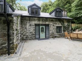 A house with a stone wall and patio area at Frongoch Old Power House in Dolgellau