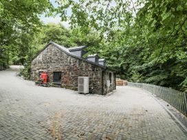An outdoor area with a stone building and a paved road at Frongoch Old Power House in Dolgellau