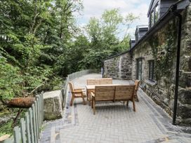 An outdoor patio with wooden furniture at Frongoch Old Power House in Dolgellau