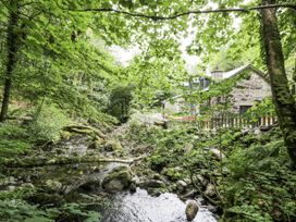 A house near a stream surrounded by trees at Frongoch Old Power House in Dolgellau