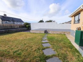 A garden with a stone pathway and deck at Morannedd Morfa Nefyn