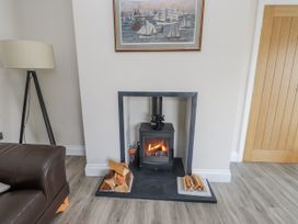 A living room with a fireplace and a lamp at Morannedd in Morfa Nefyn