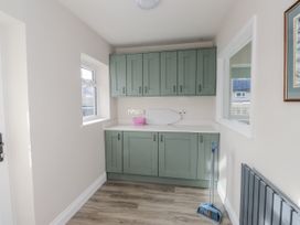 A utility room with cabinets and a window at Morannedd in Morfa Nefyn