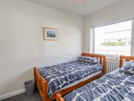 A bedroom with two beds and a window at Morannedd Morfa Nefyn