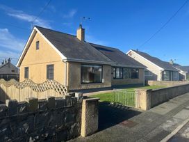 A view of a house with a fence and garden at Morannedd in Morfa Nefyn