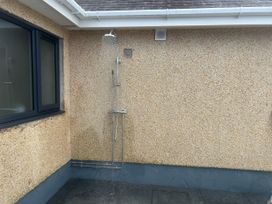 An outdoor shower on a textured wall at Morannedd in Morfa Nefyn