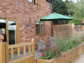 An outdoor patio area with a table, chairs, and flowers at The Cartshed in Defford