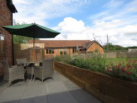 A garden with outdoor table and chairs under an umbrella at The Cartshed in Defford