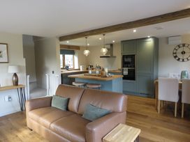 A kitchen with a sofa and kitchen island with stools at The Cartshed in Defford