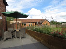 A garden with a table and chairs under an umbrella at The Cartshed in Defford
