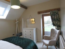 A bedroom with a bed and armchair at The Cartshed in Defford