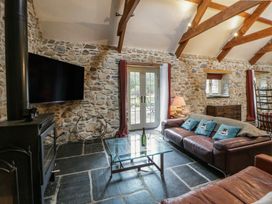 A living room with a television and a leather sofa at St Dogwells Barn near Wolfscastle