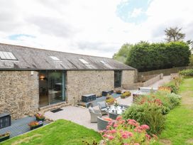 An outdoor area with seating and a stone barn at Halshanger Barn in Newton Abbot