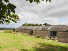 A stone building with lawn and trees at Halshanger Barn Newton Abbot