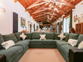 A living room with a sectional sofa and kitchen area at Halshanger Barn in Newton Abbot