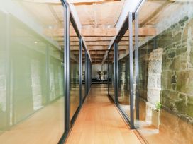 A corridor with glass walls and stone features at Halshanger Barn Newton Abbot