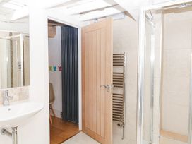 A bathroom with a sink, mirror, and shower at Halshanger Barn in Newton Abbot