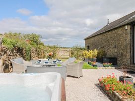An outdoor seating area with a hot tub and flowers at Halshanger Barn in Newton Abbot