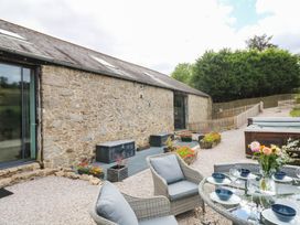 An outdoor area with a glass table and chairs at Halshanger Barn in Newton Abbot