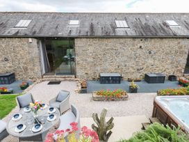An outdoor area with a stone wall, dining table and chairs at Halshanger Barn in Newton Abbot