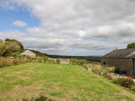A garden with a gate and flower beds at Halshanger Barn in Newton Abbot