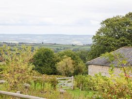 A view of fields and hills with a building and trees at Halshanger Barn in Newton Abbot