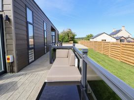 A deck with a couch overlooking grass and a fence at The Lodge @ Racecourse House Babell near Holywell