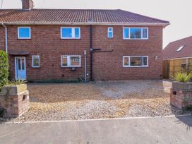 A front view of a brick house with gravel driveway and small plants at Cedar View in Hainford near Coltishall