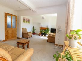 A living room with leather armchairs plants a wooden table and a television by a fireplace at Cedar View in Hainford near Coltishall