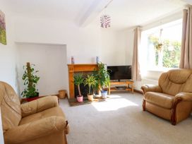 A living room with two leather armchairs plants on a fireplace and a television on a wooden stand at Cedar View in Hainford near Coltishall