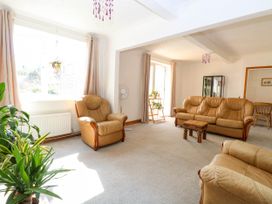A living room with beige leather armchairs and sofa plants and light curtains at Cedar View in Hainford near Coltishall