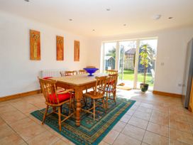 A dining room with a wooden table and chairs on a rug and glass doors leading to a garden at Cedar View in Hainford near Coltishall