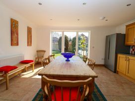A dining room with wooden table and chairs near glass doors showing a garden at Cedar View in Hainford near Coltishall